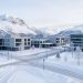 Vue hivernale réaliste du nouveau centre-ville de Kiruna en Suède, avec des immeubles modernes, des rues enneigées et des montagnes couvertes de neige sous une douce lumière arctique.